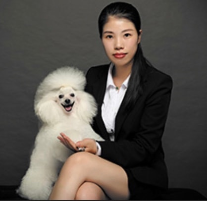 Penny in a black suit beside a white dog, a formal studio portrait